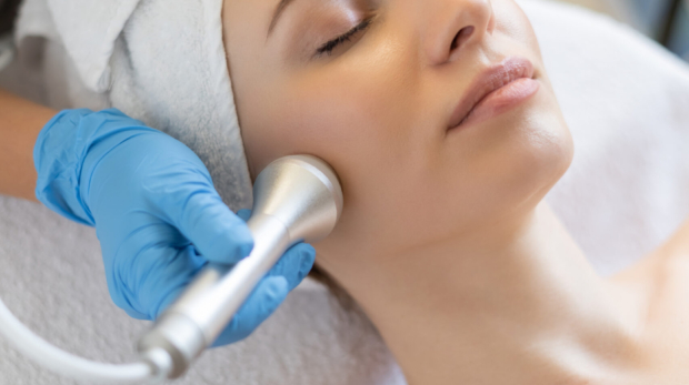 Young woman receiving a non-surgical facelift treatment at a clinic in Riyadh, cosmetologist performing skin rejuvenation on neck and face.