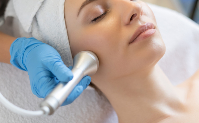 Young woman receiving a non-surgical facelift treatment at a clinic in Riyadh, cosmetologist performing skin rejuvenation on neck and face.