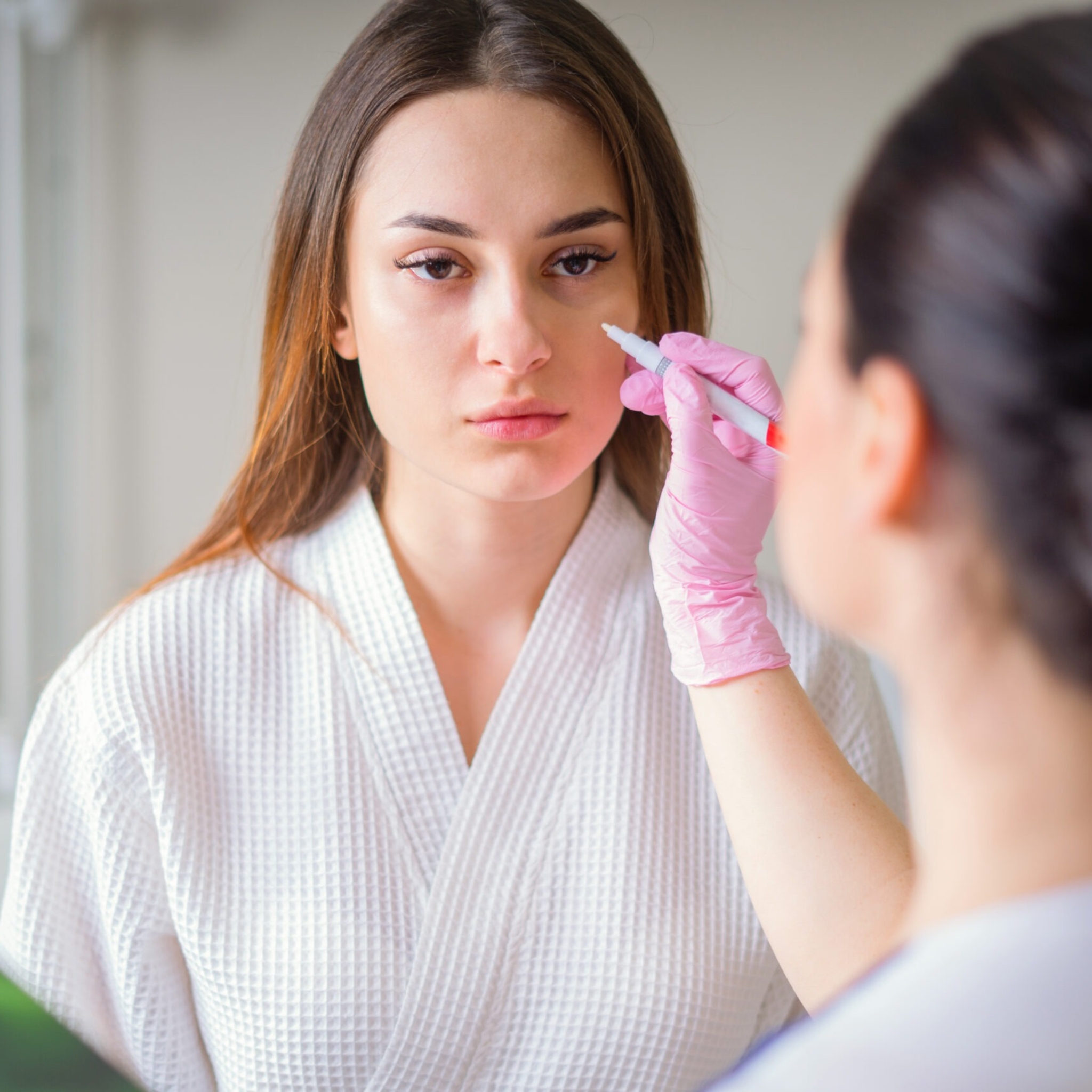 Female dermatologist examining patient’s skin during consultation at Reveal Clinics Riyadh.