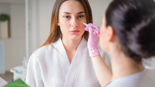 Female dermatologist examining patient’s skin during consultation at Reveal Clinics Riyadh.