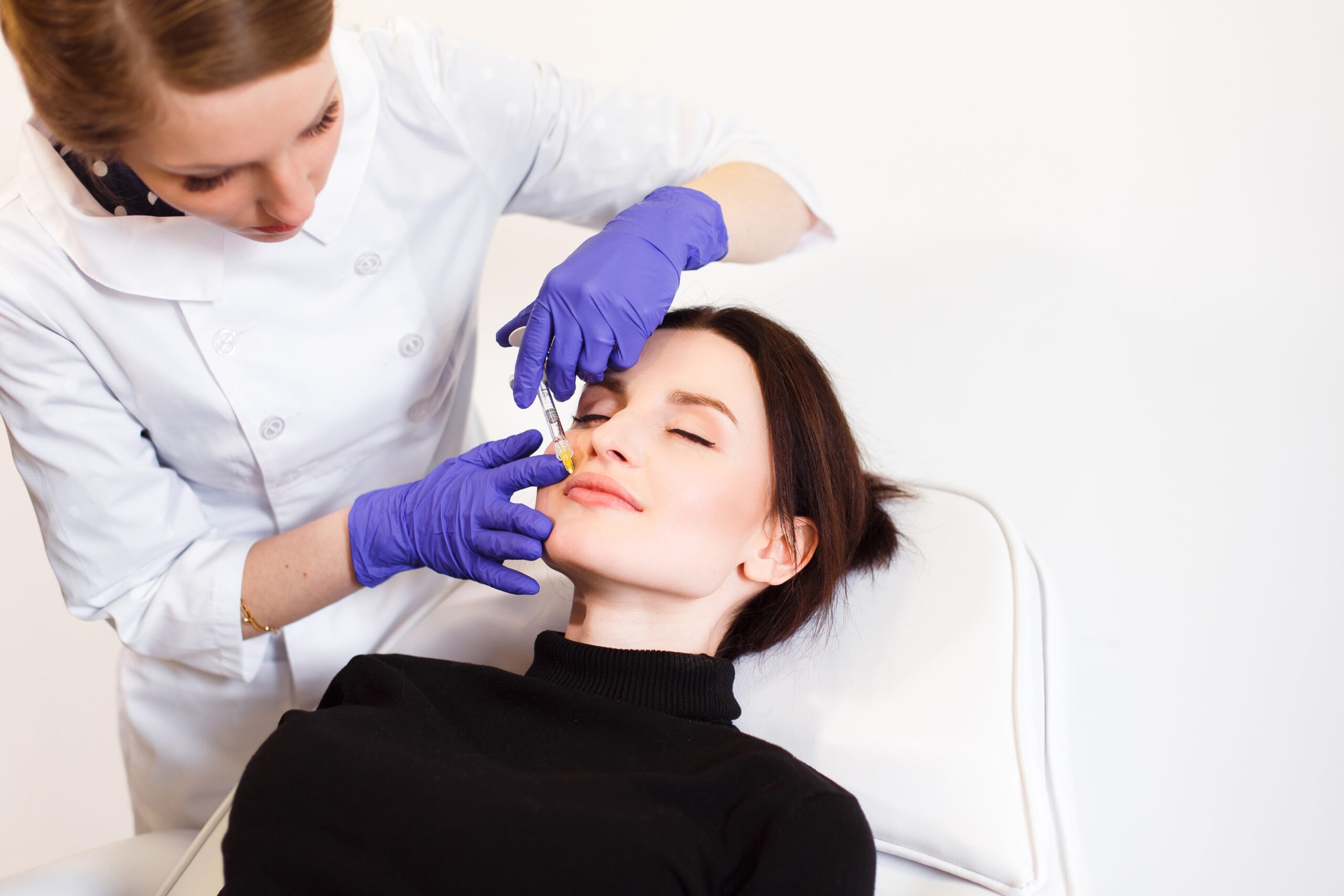 Doctor performing dermal filler injection for liquid facelift treatment in a cosmetic clinic.