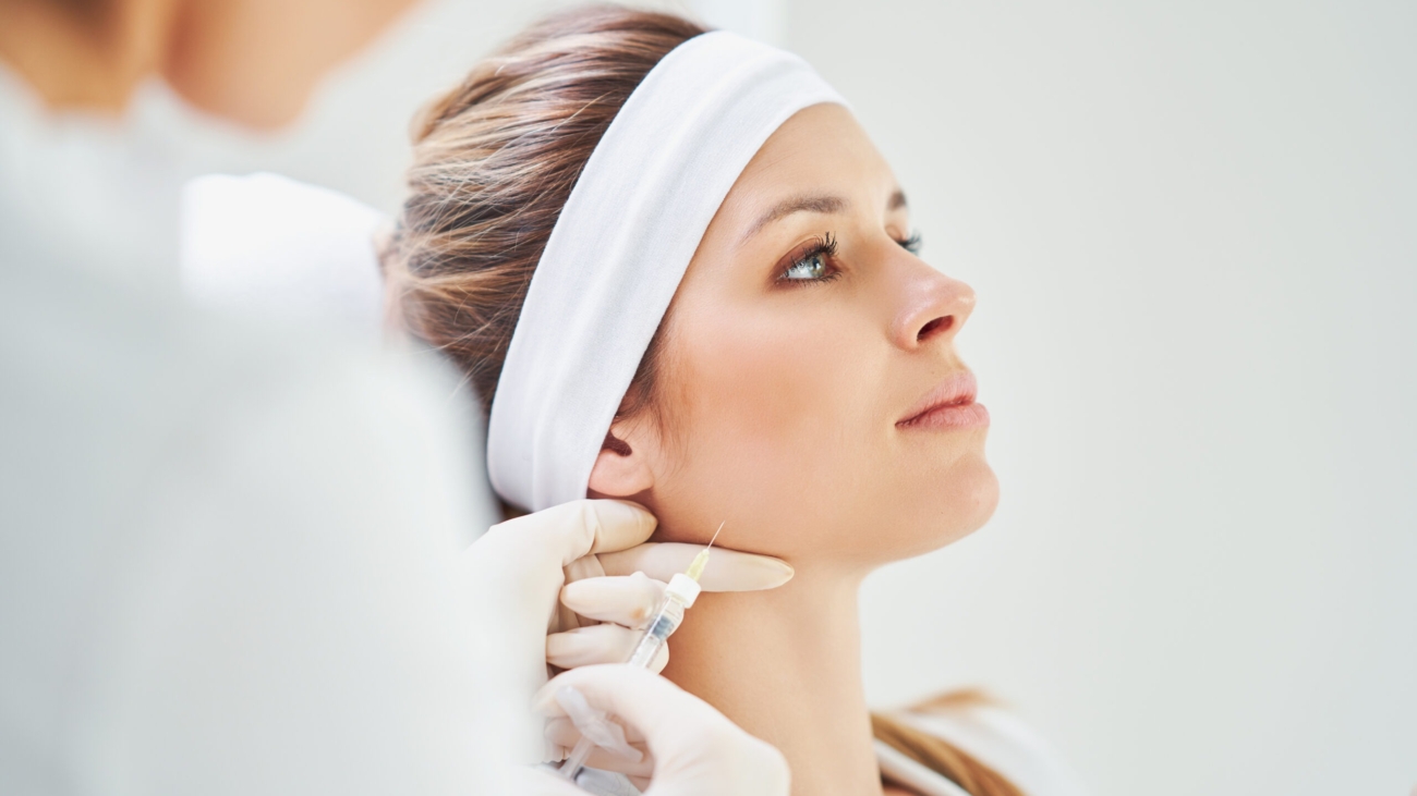 Dermatologist performing non-surgical jawline contouring with dermal fillers at Reveal Clinics Riyadh.