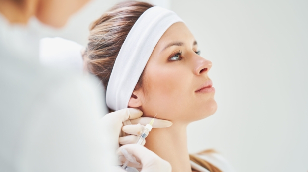 Dermatologist performing non-surgical jawline contouring with dermal fillers at Reveal Clinics Riyadh.